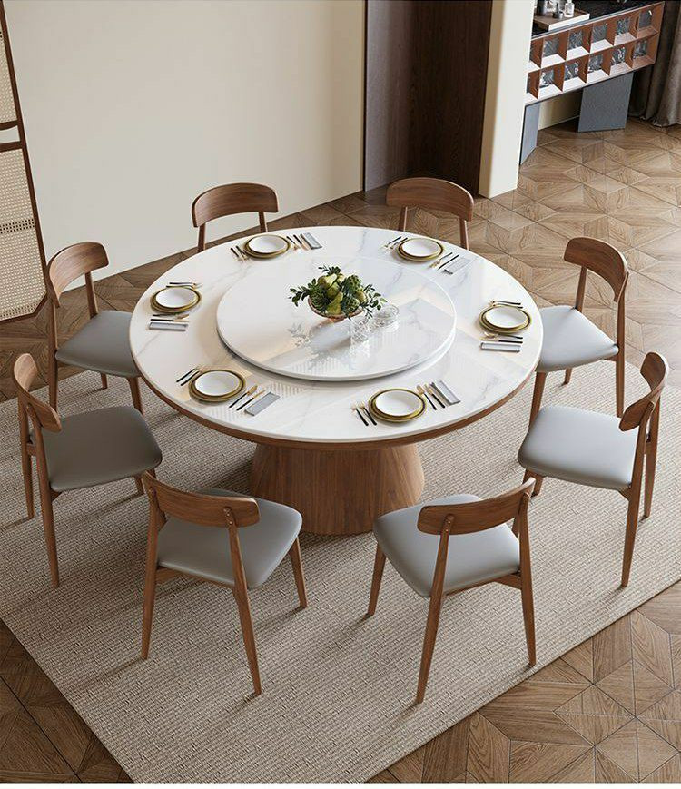 Table à manger ronde moderne en bois avec un plateau en pierre frittée et un plateau tournant central (type Lazy Susan), accompagnée de huit chaises assorties au dossier incurvé et à l'assise grise.