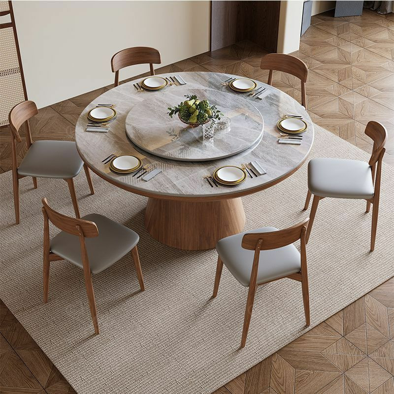 Table à manger ronde moderne en bois avec un plateau en pierre frittée et un plateau tournant central (type Lazy Susan), accompagnée de six chaises assorties au dossier incurvé et à l'assise grise.